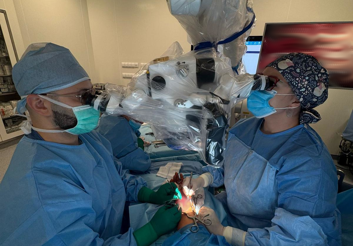 Dwoje lekarzy na sali operacyjnej w trakcie operacji przy użyciu nowego mikroskopu
