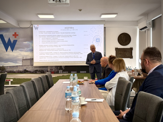 Konferencja o AI w szpitalu. Przy ekranie z agendą stoi dr Piotr Matej. Przy stole siedzą kolejno: marszałek Jarosław Stawiarski, nierozpoznana osoba, dr Małgorzata Piasecka i dr Wojciech Łucka.