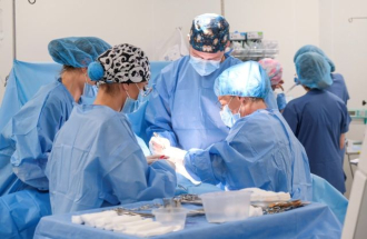 Zespół medyczny w strojach chirurgicznych przeprowadza zabieg na sali operacyjnej Oddziału Chirurgii Piersi.